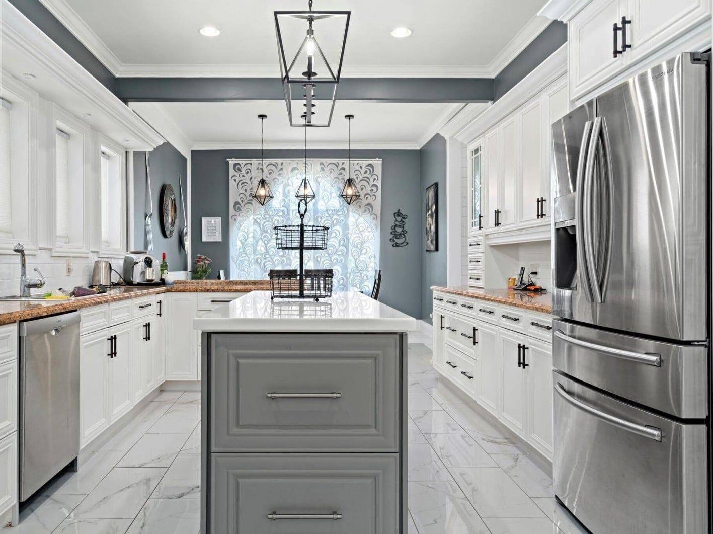 A kitchen with white cabinets , stainless steel appliances , and a large island.