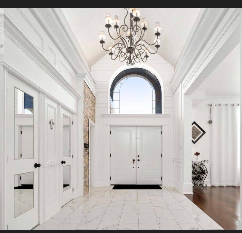 A hallway with white doors and a chandelier hanging from the ceiling