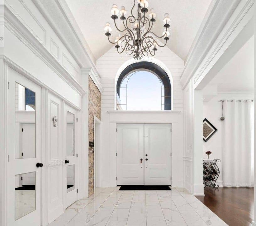 A white hallway with a chandelier hanging from the ceiling