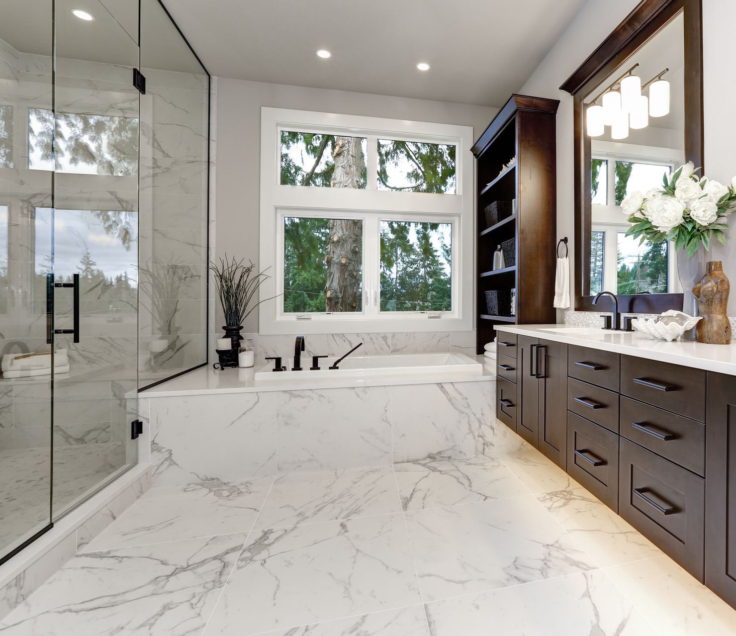 A bathroom with marble floors , a tub , a mirror , and a walk in shower.