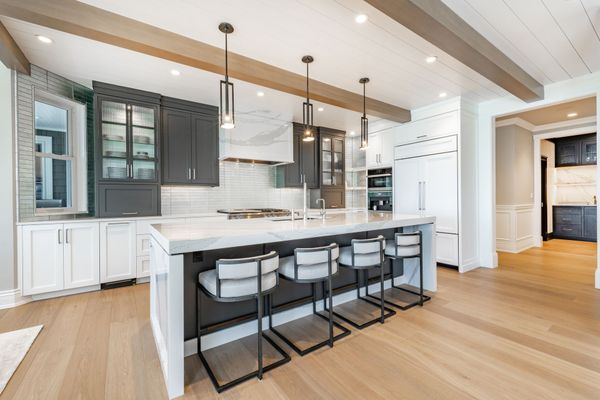 A kitchen with a large island and stools in it.