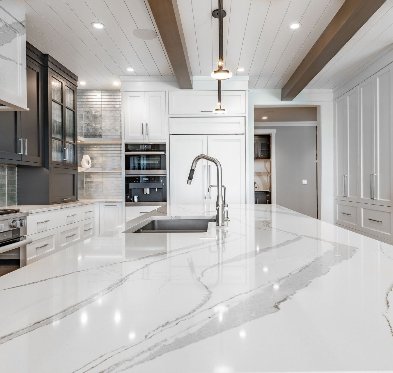 A kitchen with white cabinets , granite counter tops , a sink , and a refrigerator.