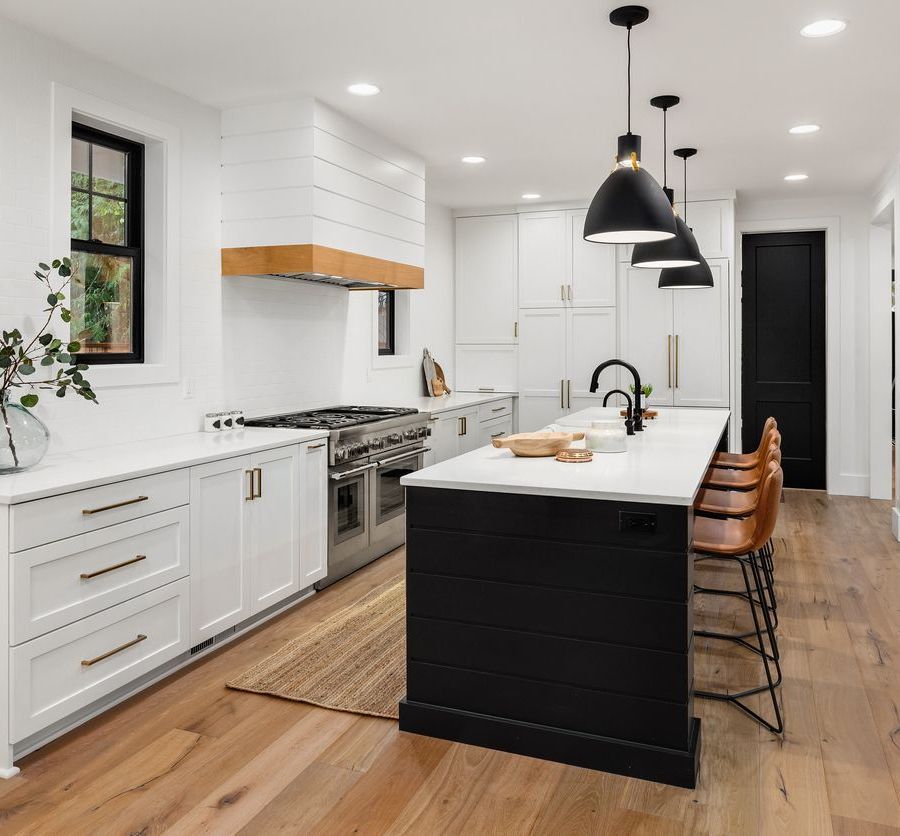 A kitchen with white cabinets and a black island.