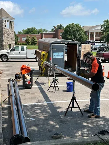 Rooftop solar panel installer in orange vest and hard hat working on panels during sunset.