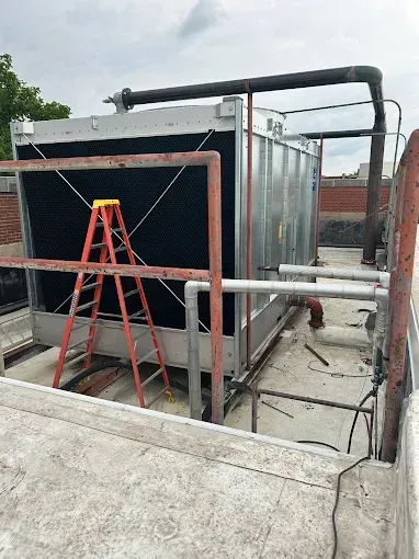 Solar panel installer in orange safety gear on a rooftop, working on panels in the sun.