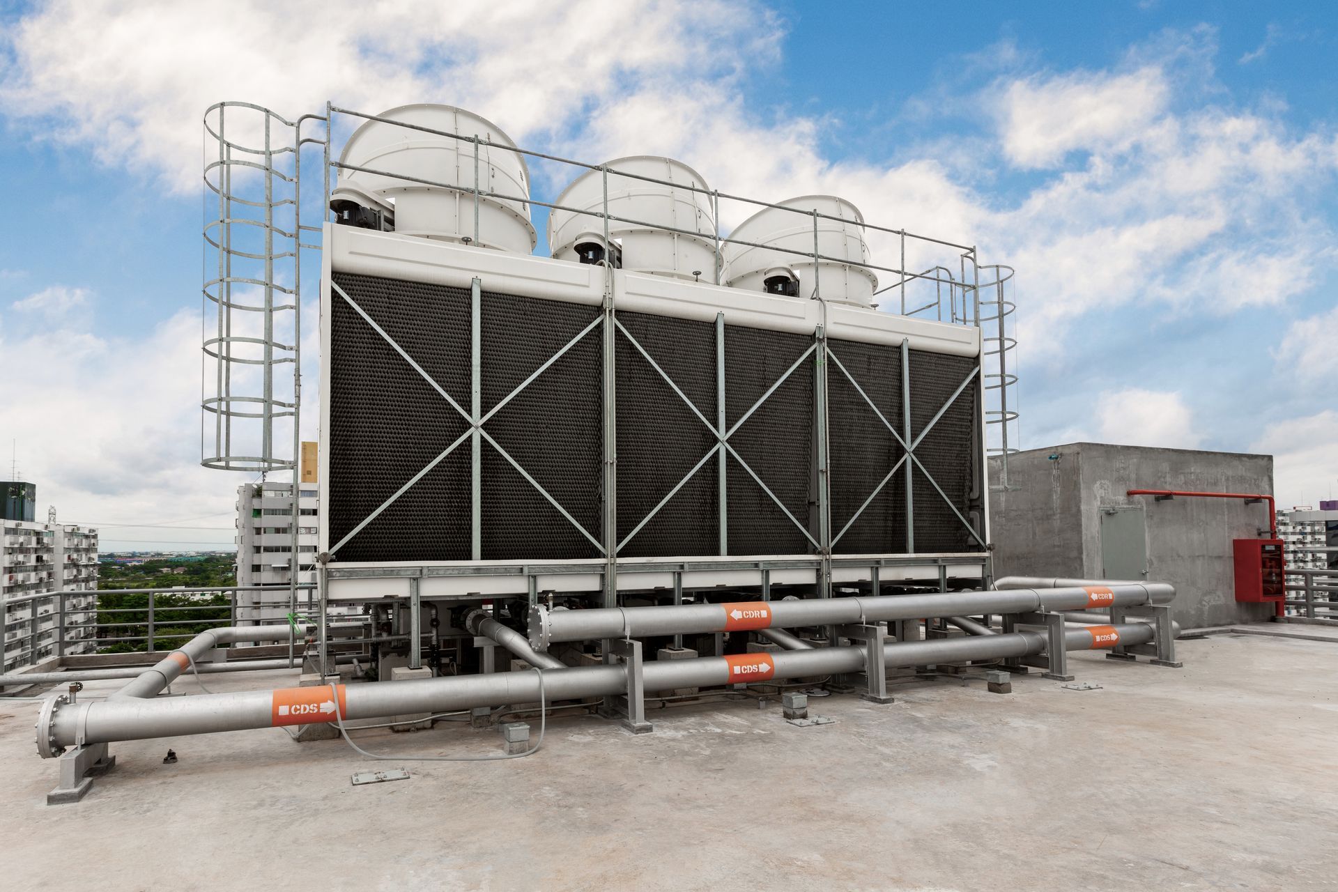 Cooling towers on a rooftop against a cloudy sky.