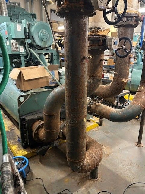 Industrial machinery with rusty pipes and valves in an industrial setting.