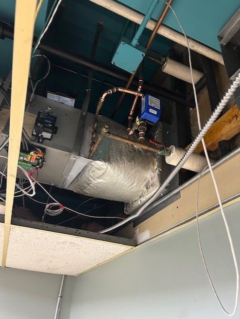 HVAC unit installed in a ceiling. Copper pipes, electrical wiring, and insulation visible.