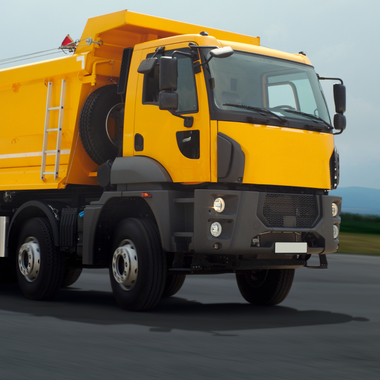 A yellow dump truck is parked on the side of the road