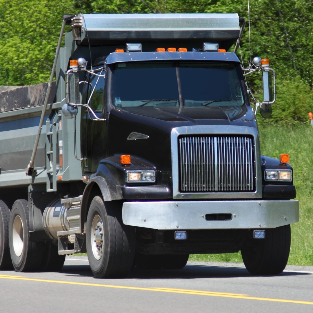 A black dump truck is driving down the road