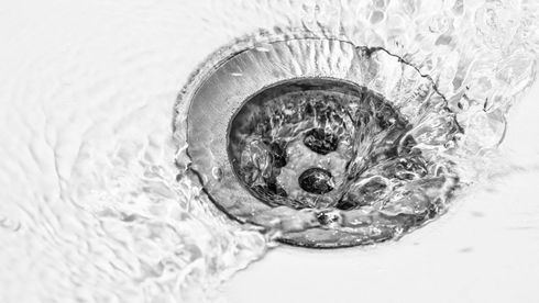 A black and white photo of water running down a drain.