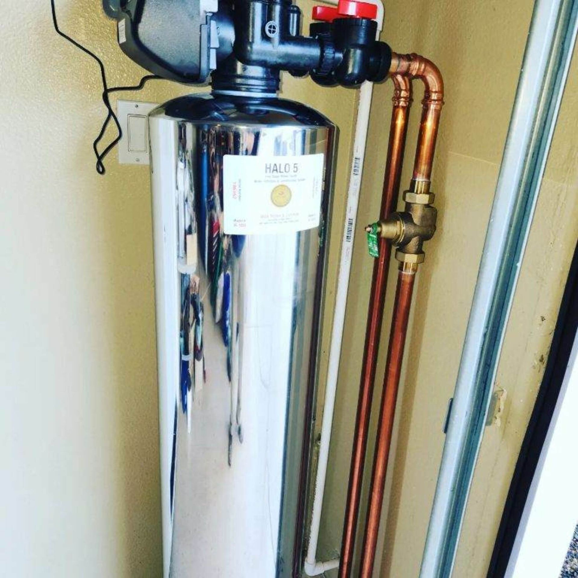 A stainless steel water heater with copper pipes attached to it