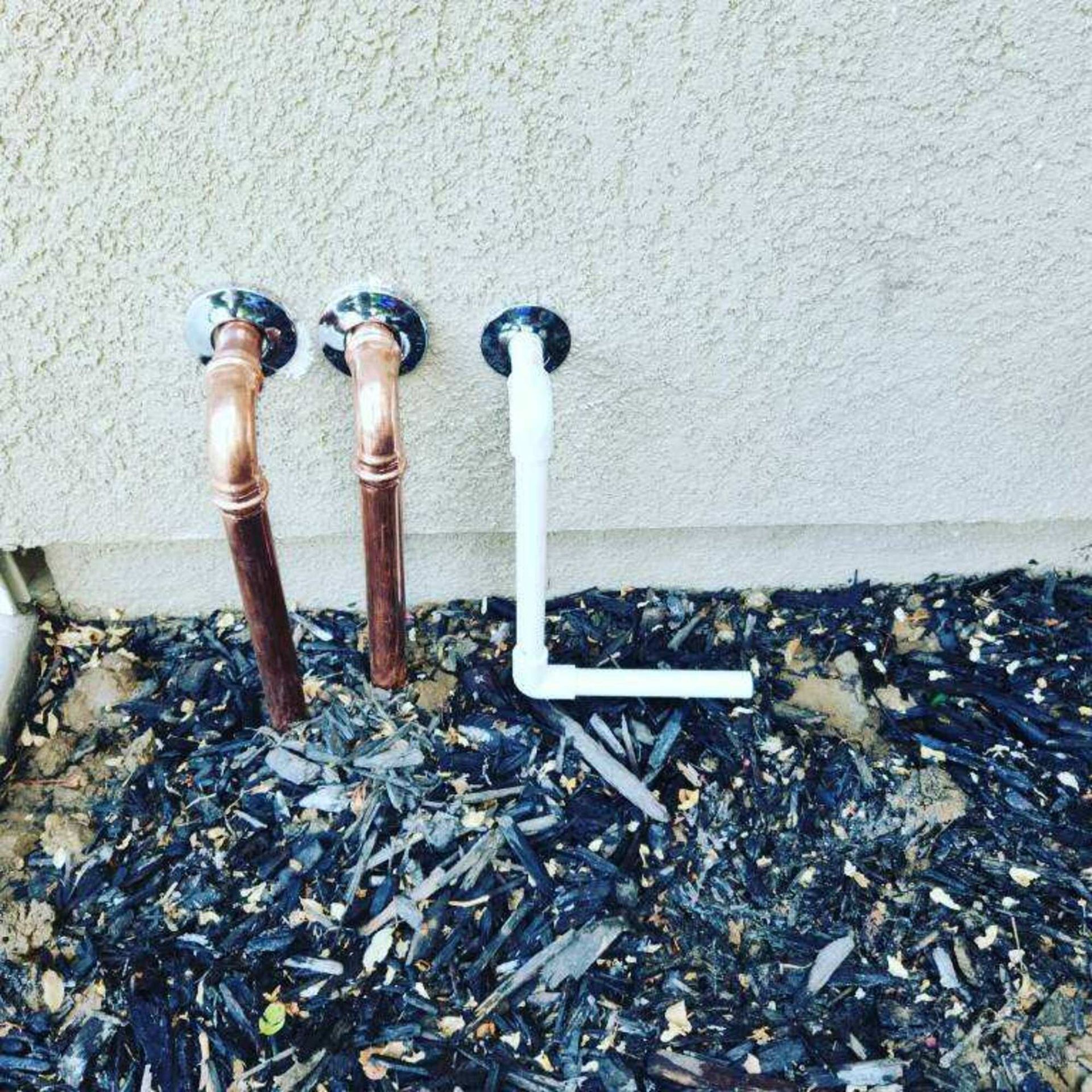 Two copper pipes are connected to a white pipe.