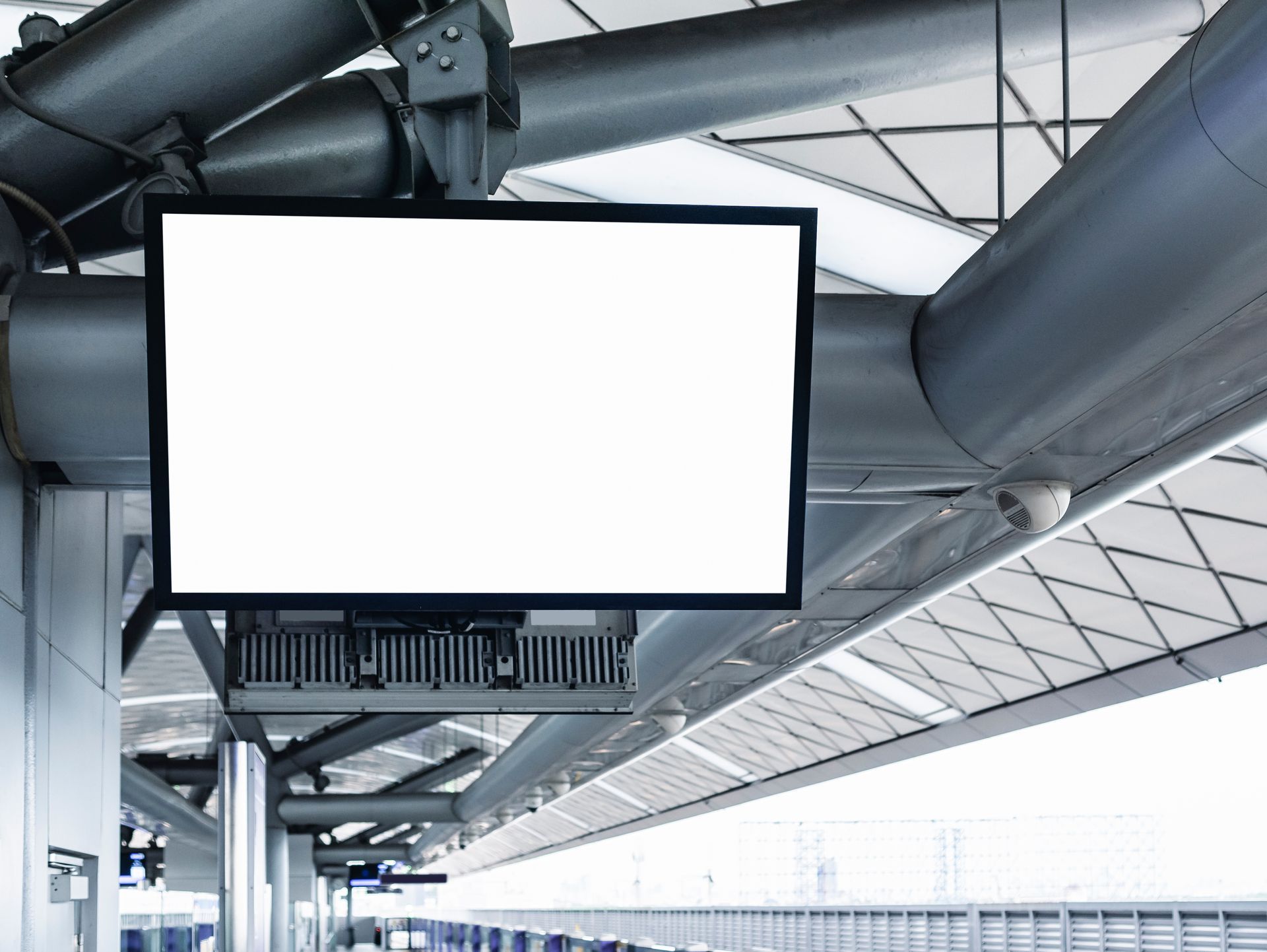A blank digital display screen suspended from the ceiling in a train station.