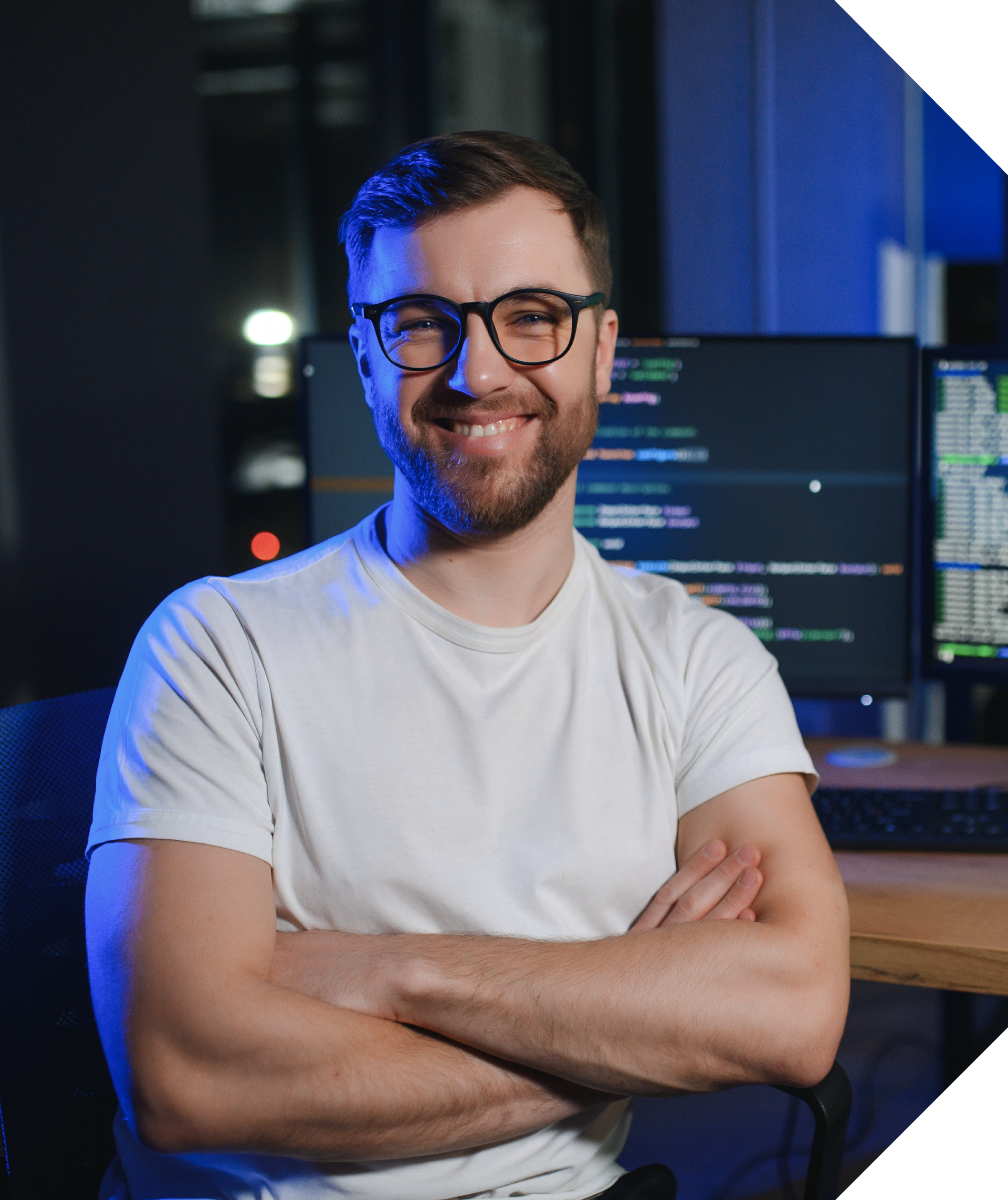 Man with glasses smiles, arms crossed, in front of computer screens with code. Blue-lit room. Hercules FX