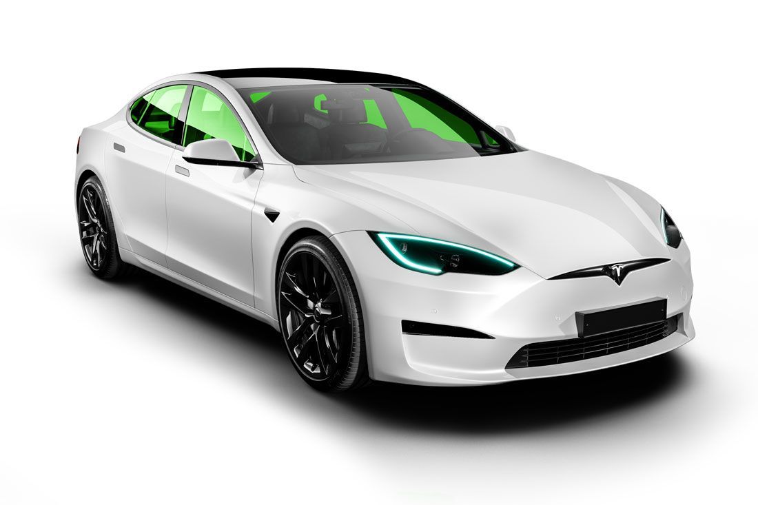 White Tesla sedan with black wheels, tinted green windows, and glowing blue headlights.