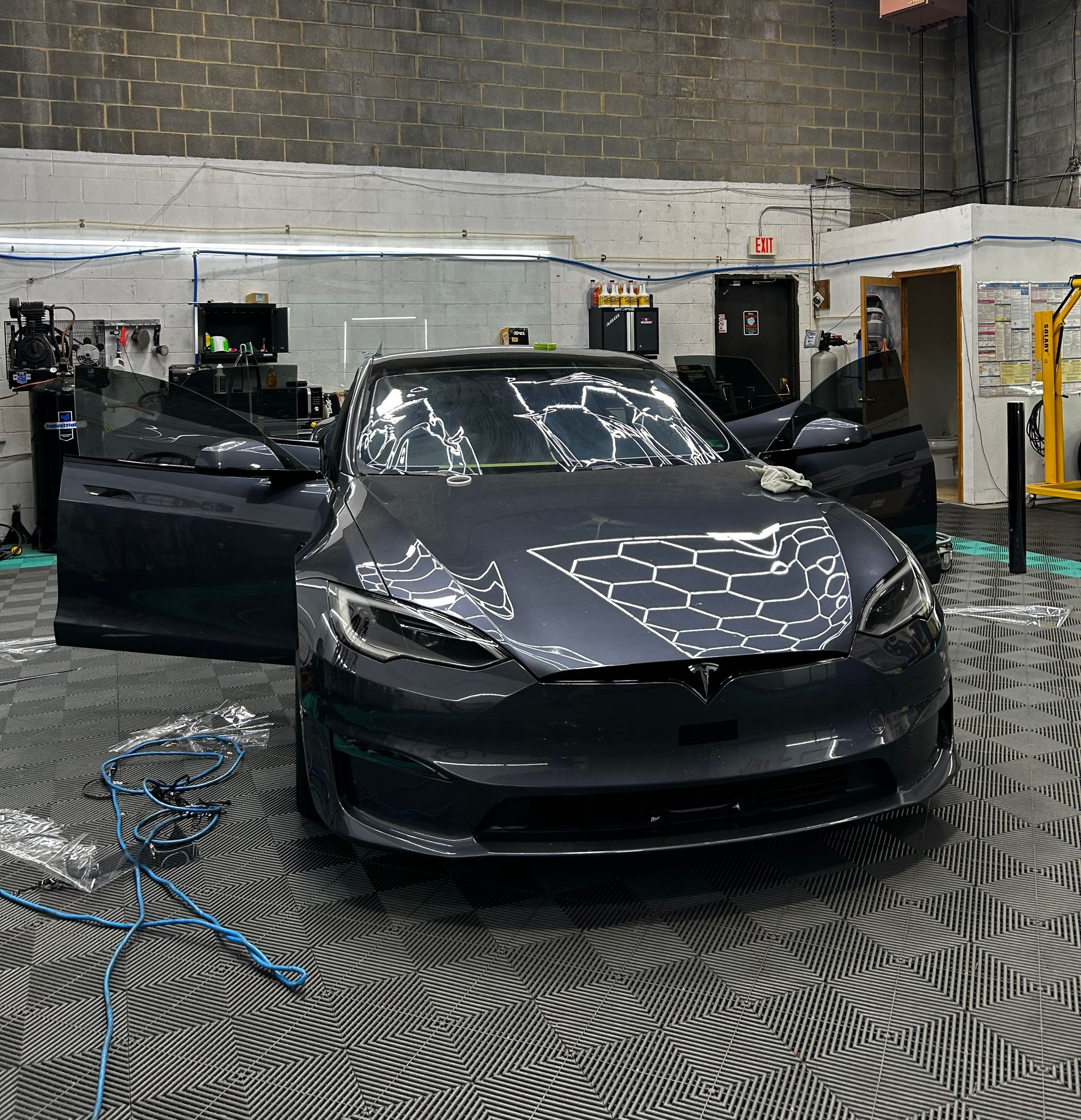 A man is cleaning a white maserati car in a garage.