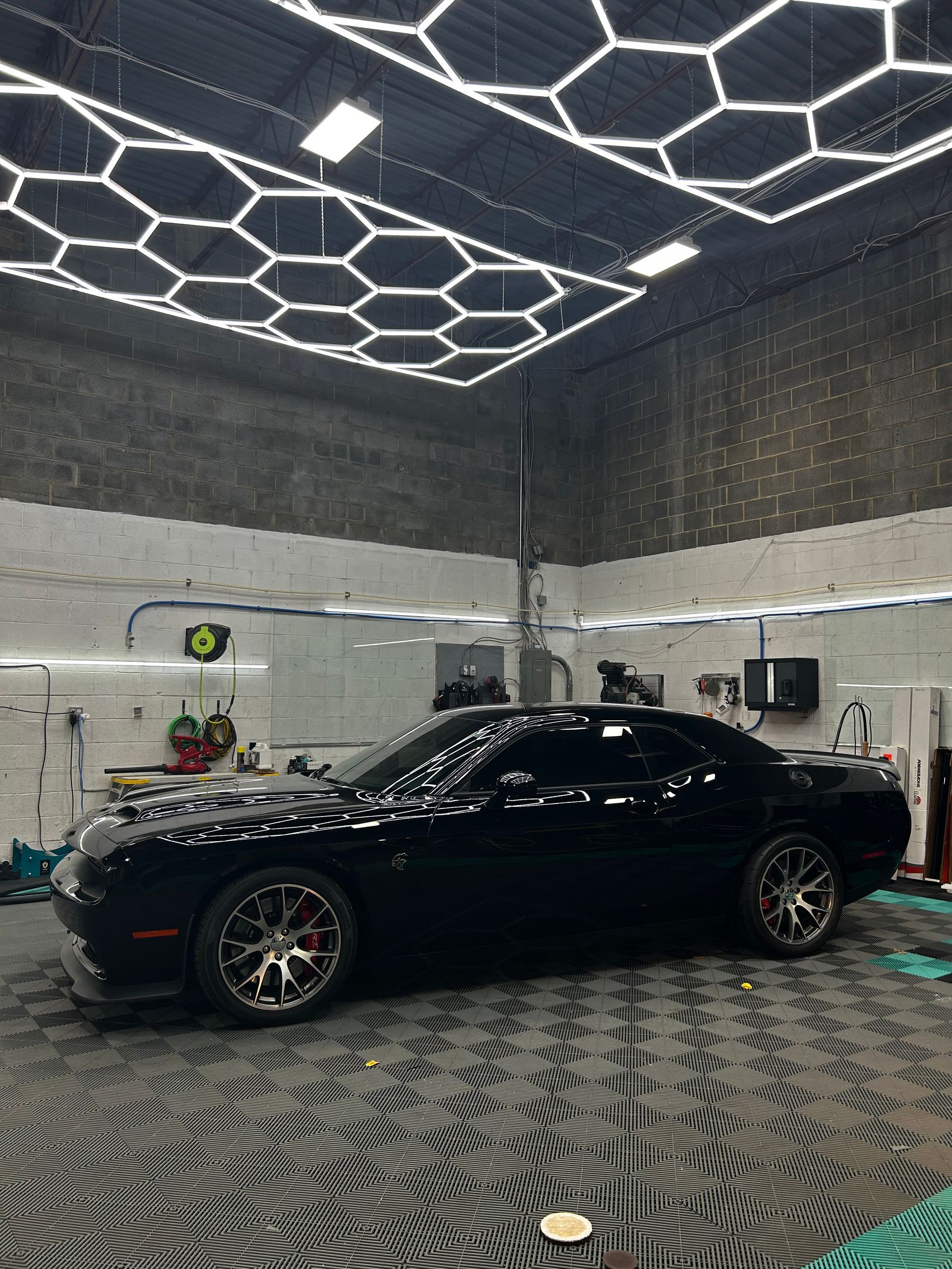 A black dodge challenger is parked in a garage.