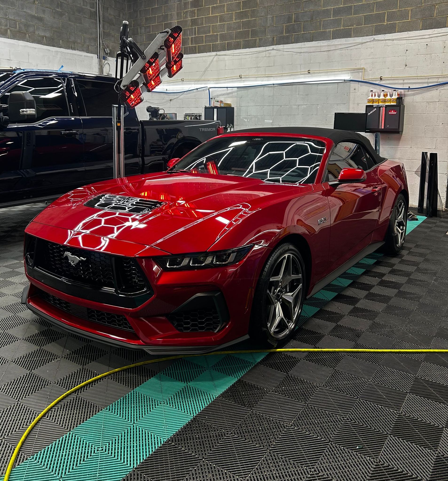 A red mustang convertible is sitting in a garage.