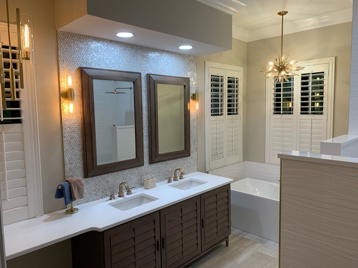 A modern bathroom with a double vanity, dark wood cabinets, dual mirrors, a tiled backsplash, and a corner bathtub.