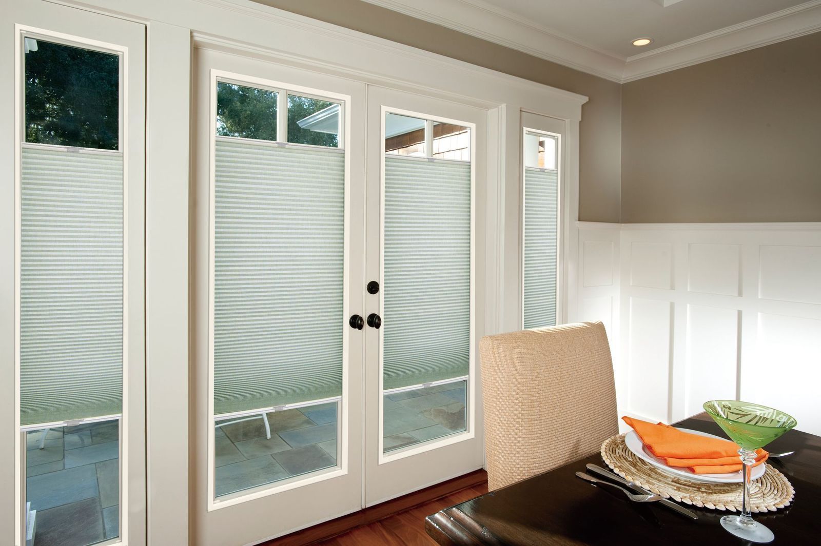 French doors and side windows covered with pleated light-filtering cellular shades in a dining room.