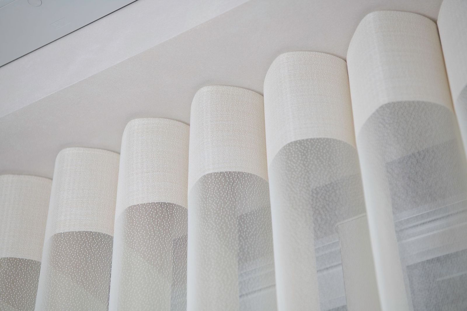 Close-up of white wave-fold curtains hanging from a ceiling track.