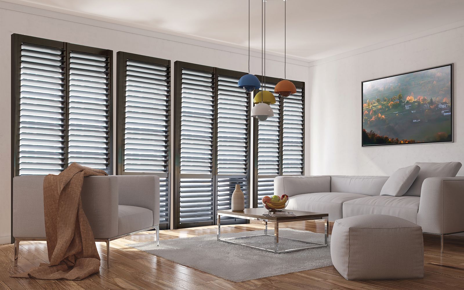 A modern, sunlit living room featuring grey sofas, a patterned rug, wooden floors, and dark window shutters.