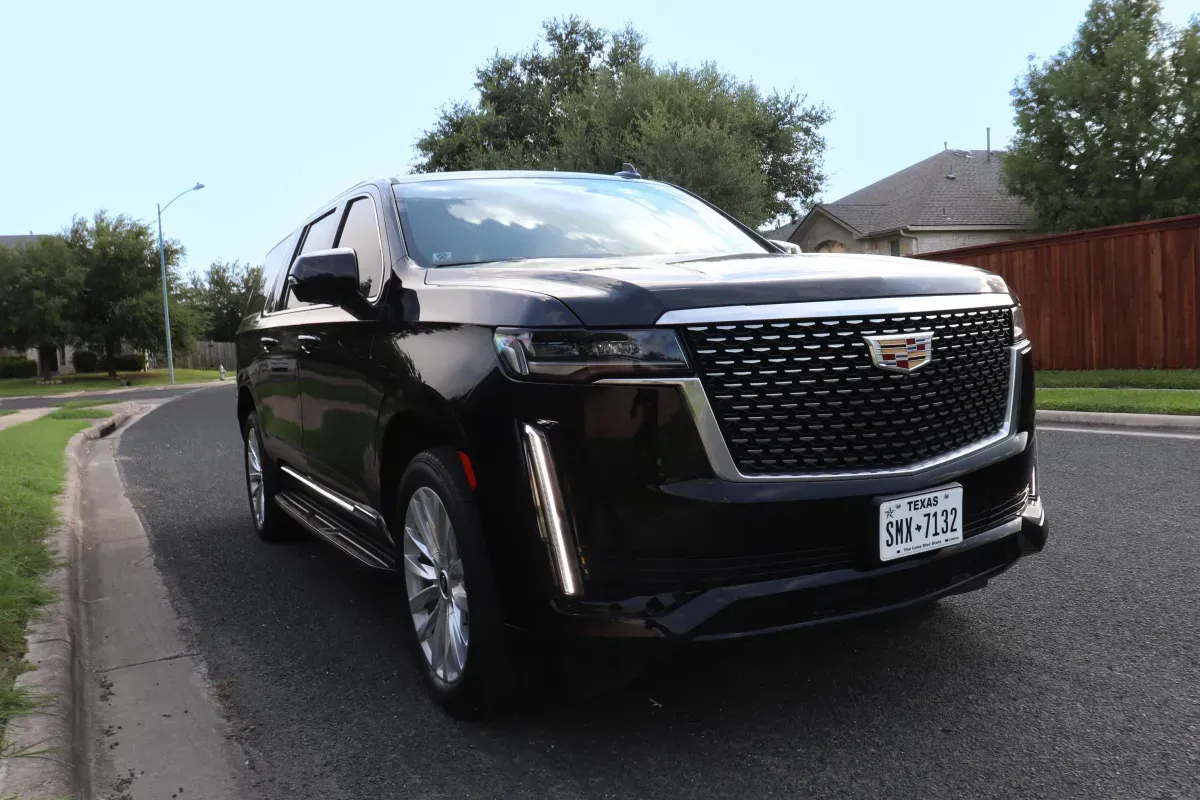 Black Cadillac SUV parked on a residential street; front view.