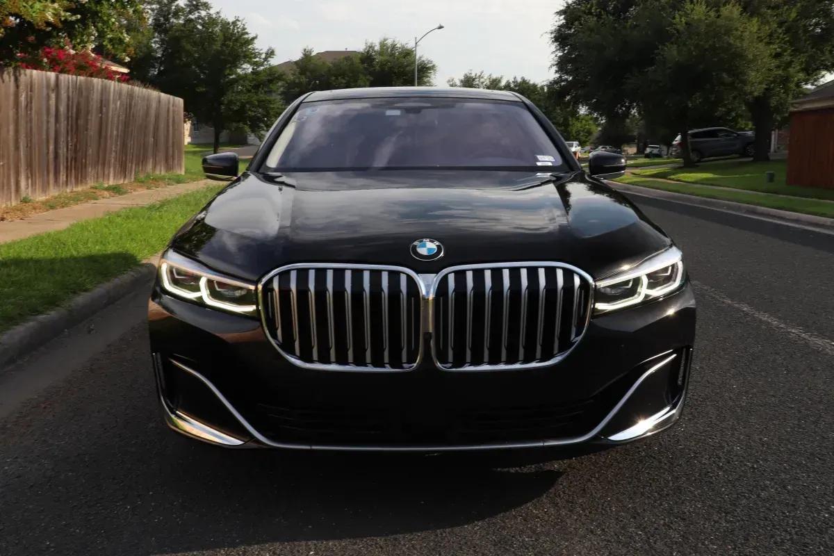 Black BMW sedan parked on a street, front view showing the grille and headlights.