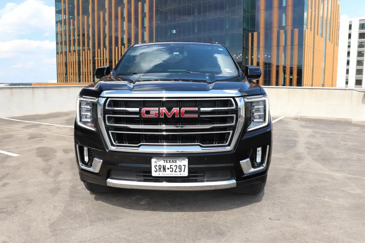 Black GMC Yukon SUV parked in front of a modern building, license plate visible.