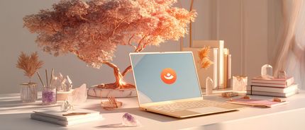 Computador portátil sobre uma mesa com o ecrã a exibir um símbolo de download, ao lado de livros e objetos decorativos.