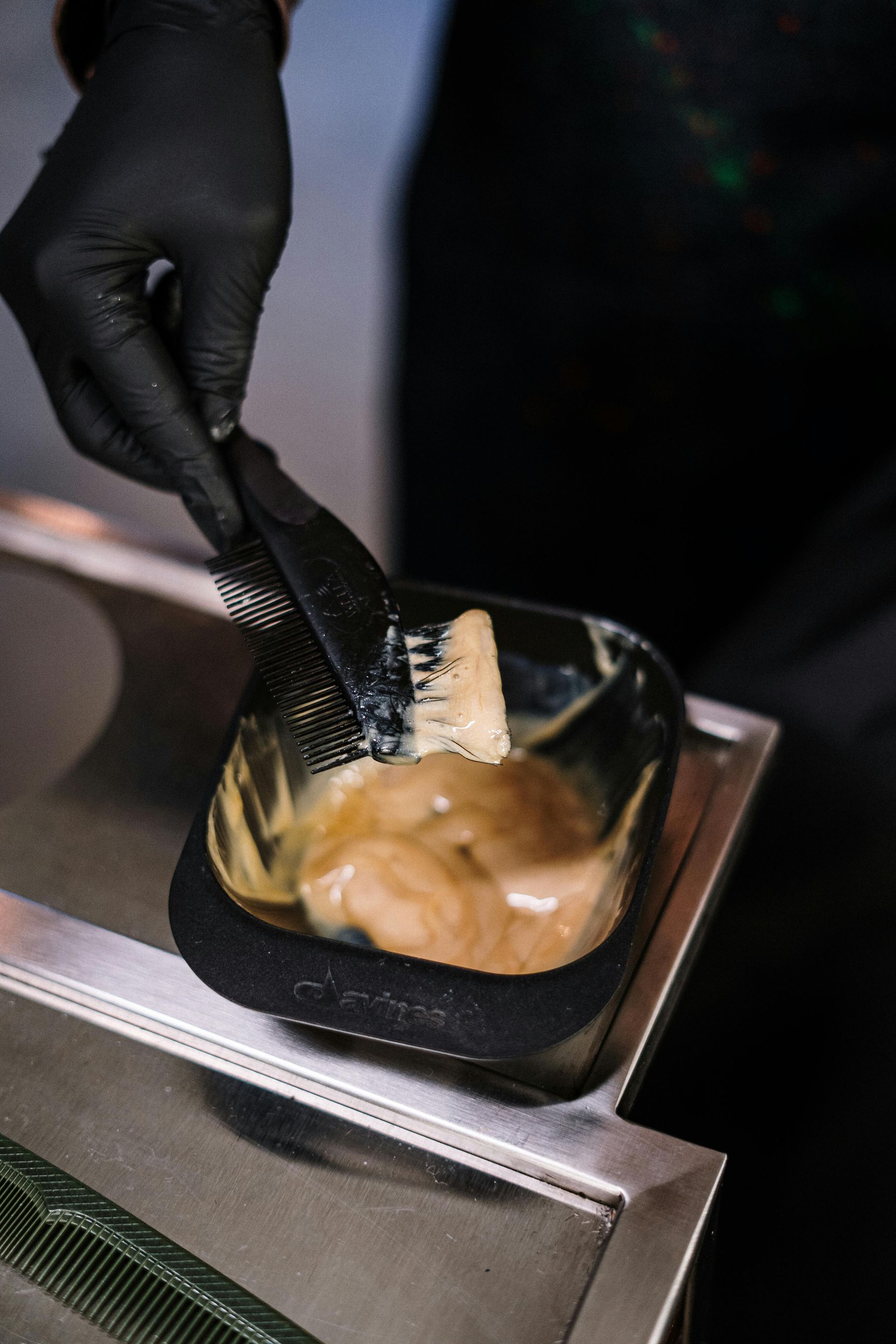 A person is applying hair dye to a bowl with a brush.
