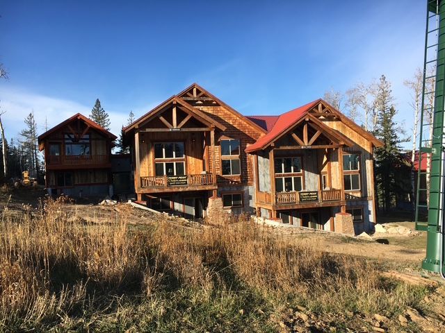 A gray deck with a white railing and trees in the background