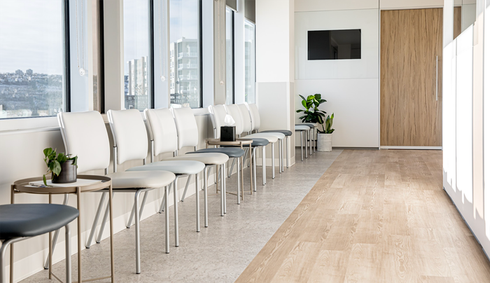 Waiting room with white chairs, side tables, and a window view.