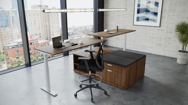Modern office with a height-adjustable desk, a black chair, and a cabinet against a window with city views.
