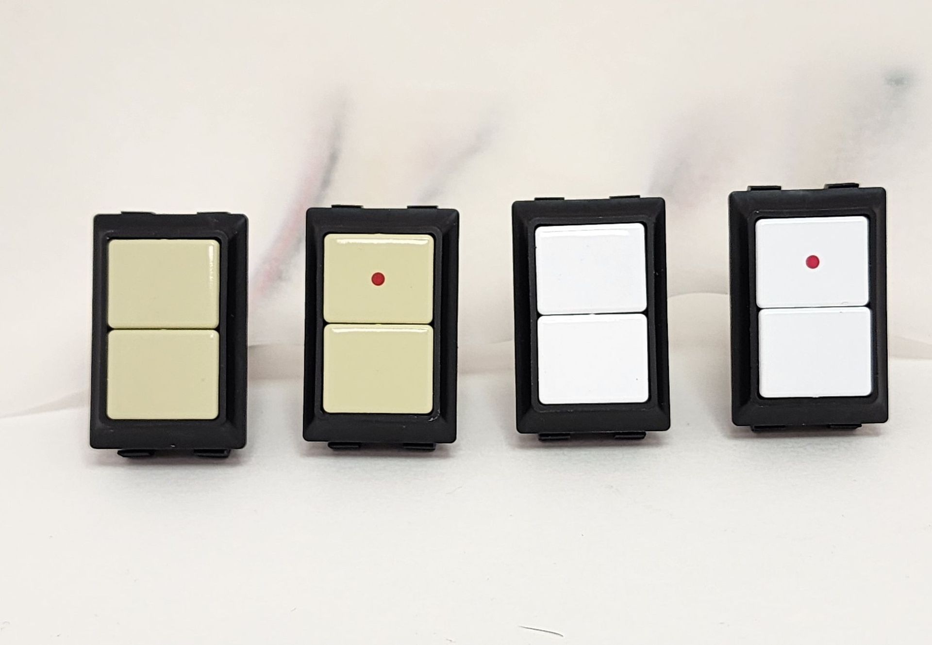 Four different colored light switches are lined up on a table