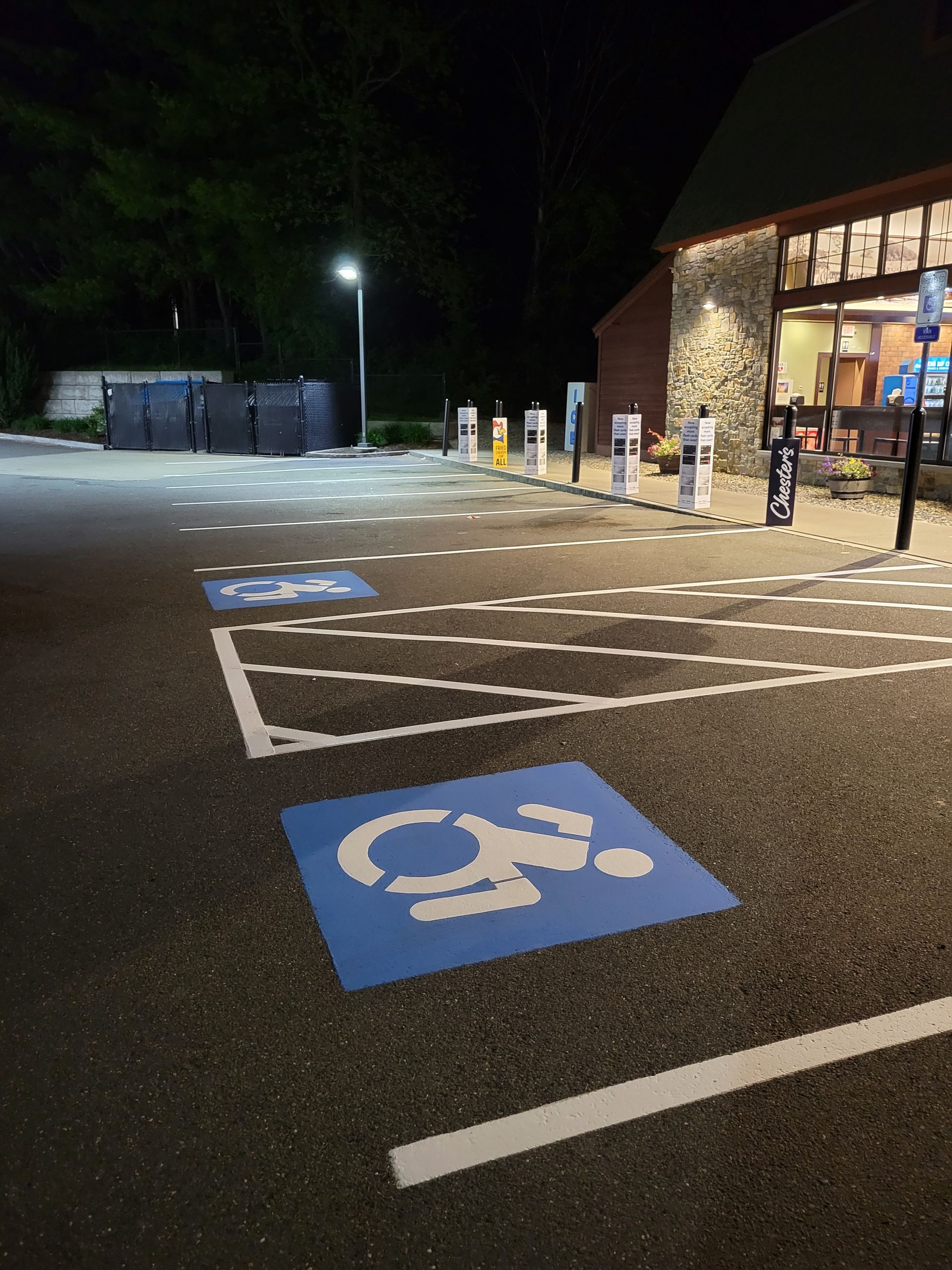 Parking lot with blue handicap parking spaces, vehicle in a space, and other cars in the background.
