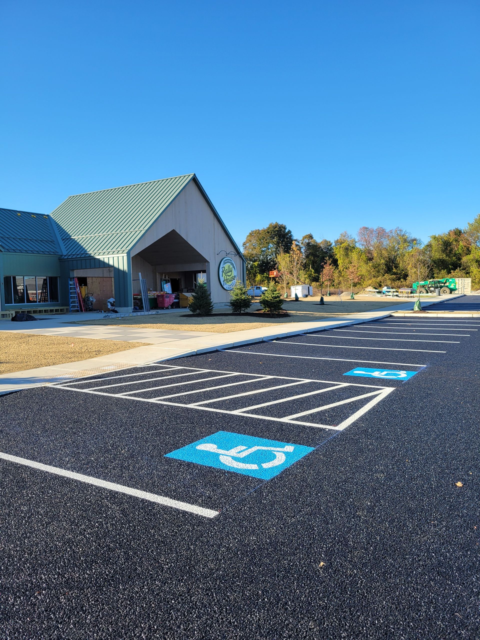 Empty parking lot in front of a single-story commercial building under a clear blue sky.