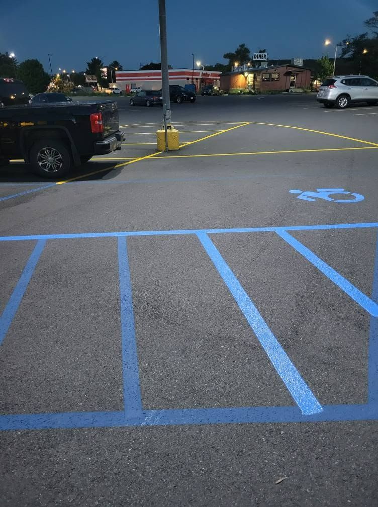 Parking lot with blue handicap space markings and a dark pickup truck.