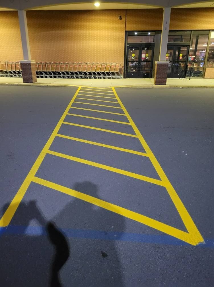Brick building with angled windows, next to a parking lot under a blue sky.