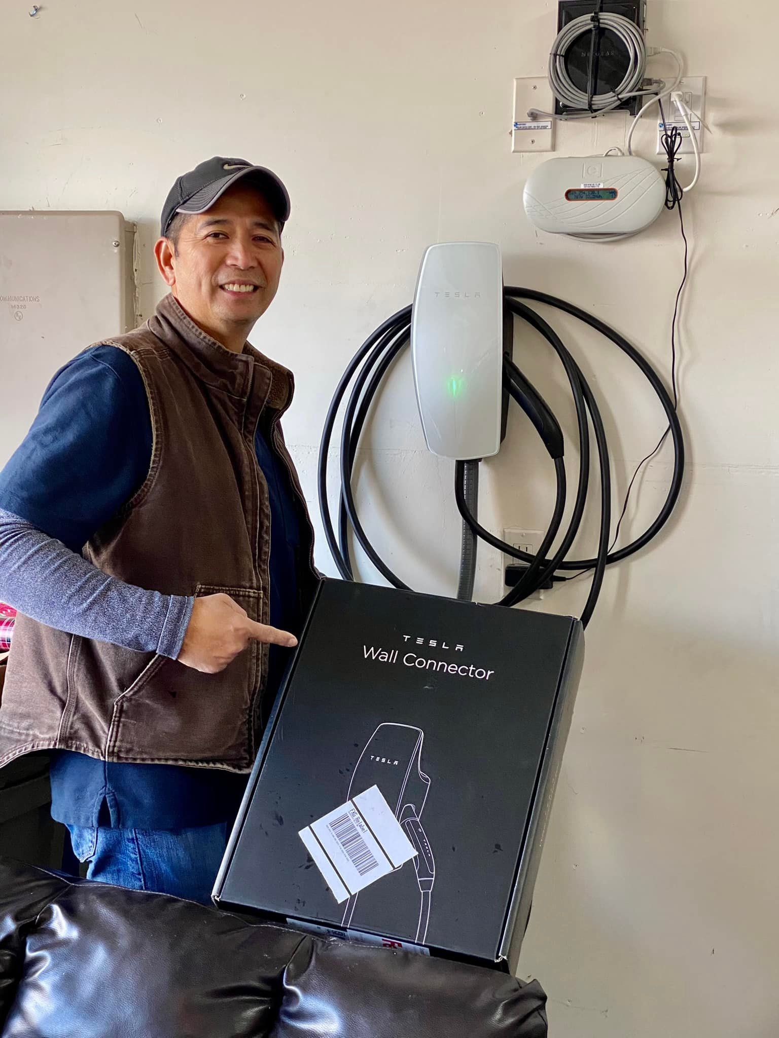 A man is holding a box in front of a wall charger.