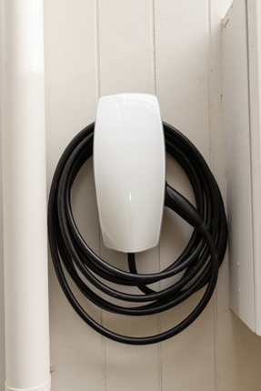 A white mouse is connected to a black cable on a white wall.