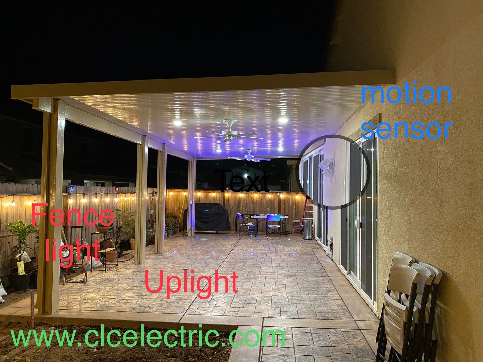 A patio with a ceiling fan and lights on it at night.