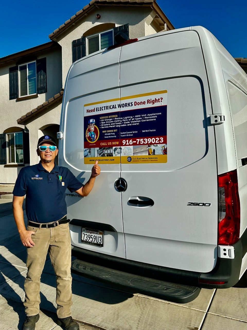 A man is standing in front of a white van in front of a house.
