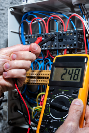 A person is using a multimeter to test a circuit board.