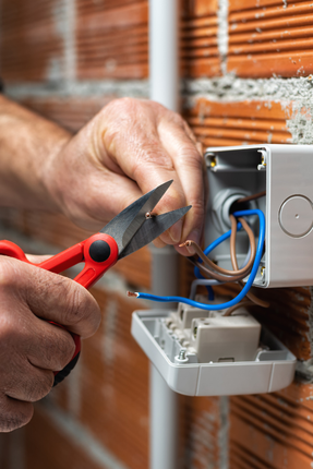 A person is cutting a wire with a pair of scissors.