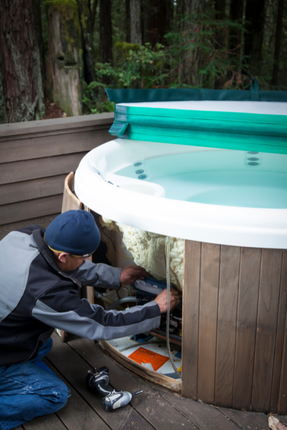 A man is working on a hot tub on a deck.