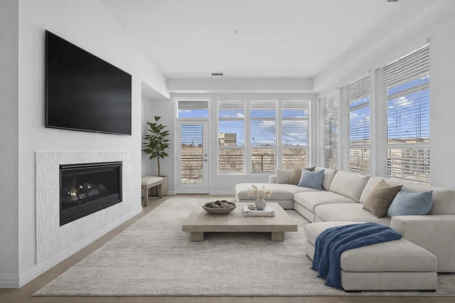 Bright modern living room with sectional sofa, fireplace, wall TV, and large windows with a mountain view.