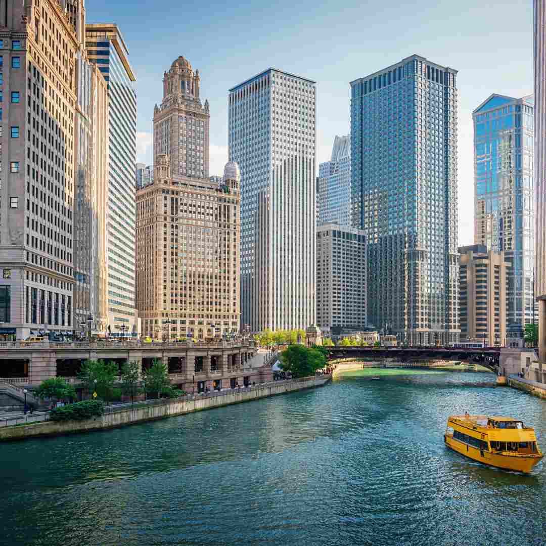 Yellow boat navigating the Chicago River with city skyline in background