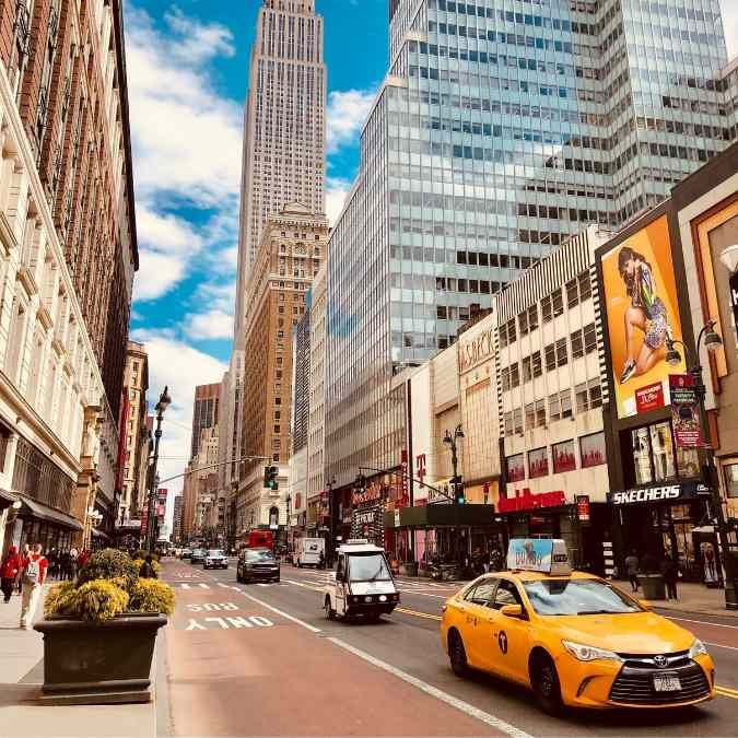 Busy New York City street scene with a yellow taxi in traffic